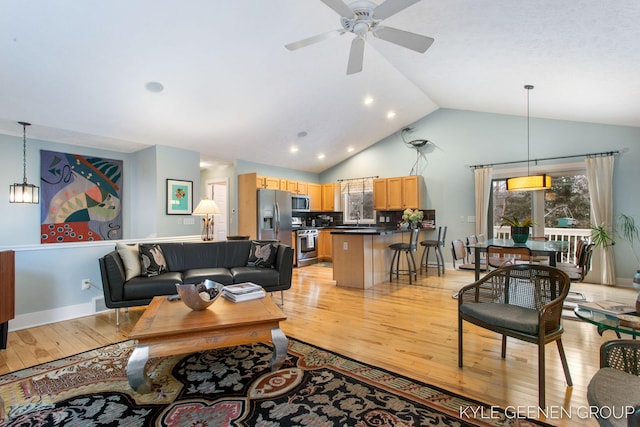 living room featuring light wood finished floors, a ceiling fan, baseboards, and high vaulted ceiling