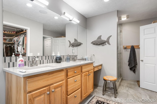 bathroom with a spacious closet, a sink, a shower stall, and double vanity