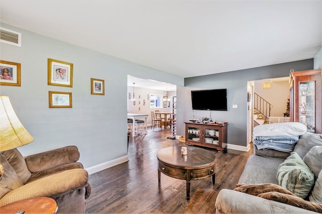 living area with visible vents, stairway, dark wood-type flooring, a chandelier, and baseboards