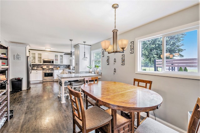 dining room with dark wood finished floors, baseboards, and an inviting chandelier