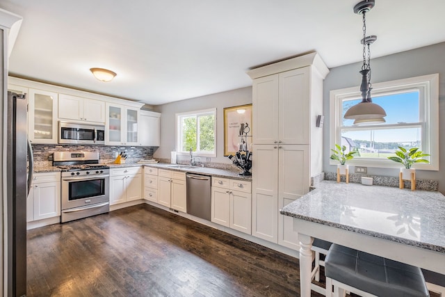 kitchen with light stone countertops, dark wood-style floors, stainless steel appliances, and a sink