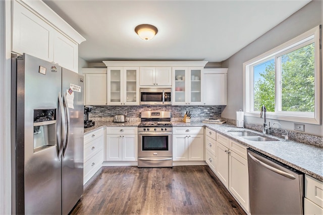 kitchen featuring stainless steel appliances, white cabinetry, a sink, and tasteful backsplash