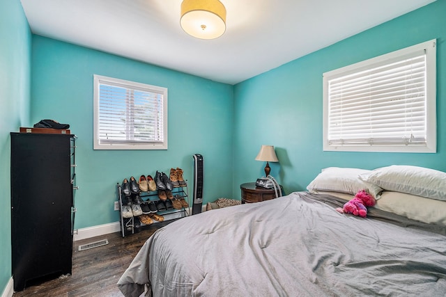 bedroom with dark wood finished floors, visible vents, and baseboards