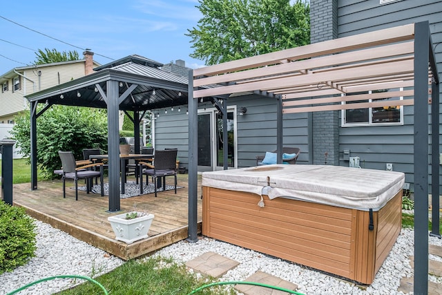 wooden terrace featuring outdoor dining area, a hot tub, and a gazebo