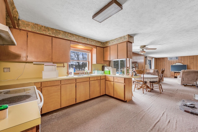 kitchen with wood walls, a ceiling fan, light countertops, and a textured ceiling