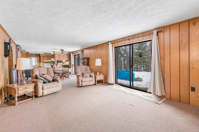 unfurnished living room with carpet floors, a textured ceiling, wooden walls, and a wealth of natural light