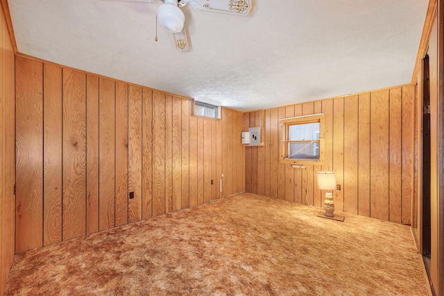 carpeted empty room with ceiling fan and wooden walls