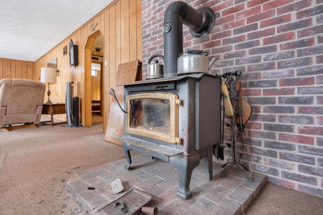 room details featuring carpet floors, a wood stove, and wooden walls