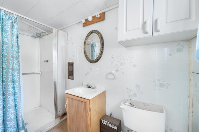 bathroom with a shower stall, tile walls, and vanity