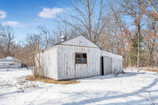 snow covered structure with an outbuilding