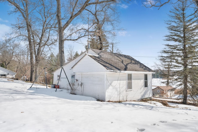 snow covered property with roof with shingles and a detached garage