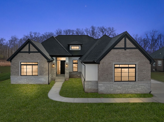 modern farmhouse featuring a shingled roof, a lawn, and brick siding