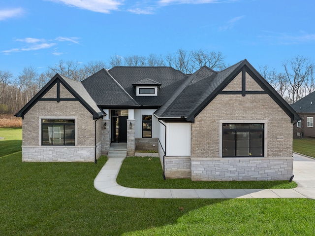 view of front of home with a shingled roof, a front yard, and brick siding