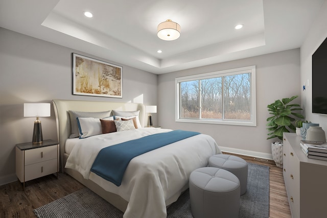 bedroom with a tray ceiling, dark wood-style flooring, baseboards, and recessed lighting