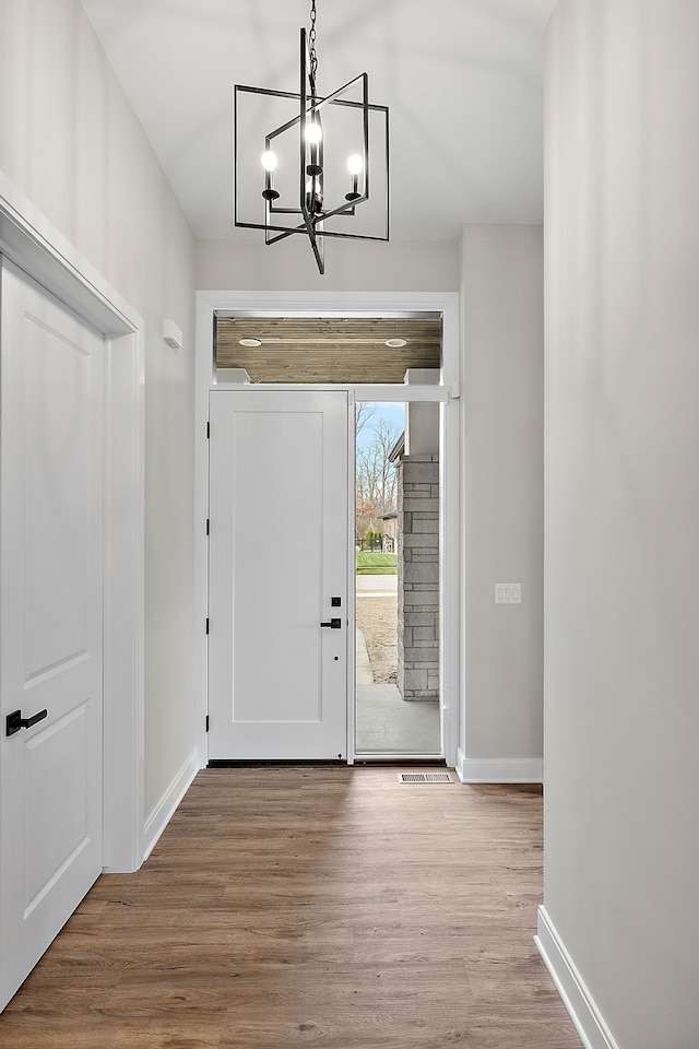 entryway with a notable chandelier, baseboards, and wood finished floors