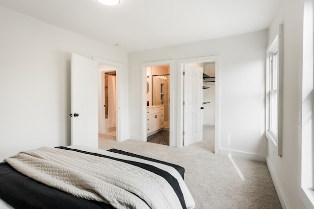 bedroom featuring ensuite bathroom, carpet floors, a walk in closet, and baseboards