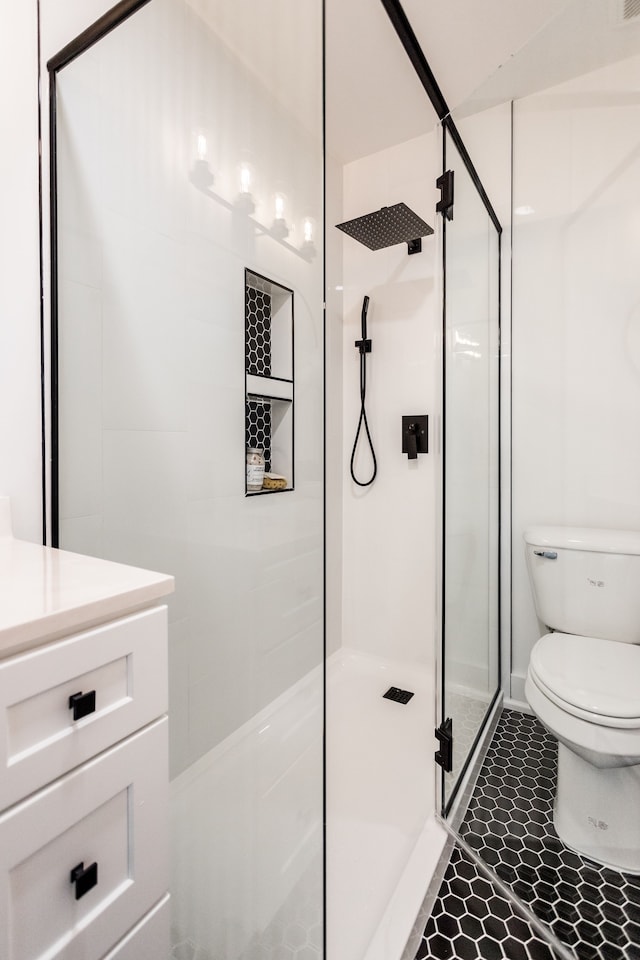 bathroom featuring toilet, a stall shower, vanity, and tile patterned floors