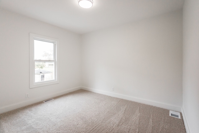 empty room with carpet floors, visible vents, and baseboards