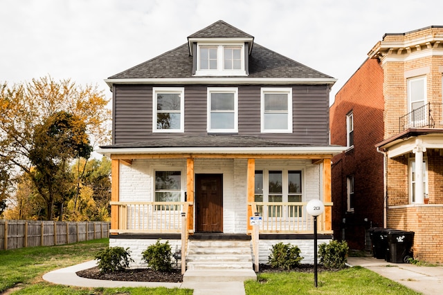 traditional style home featuring a shingled roof, covered porch, and fence