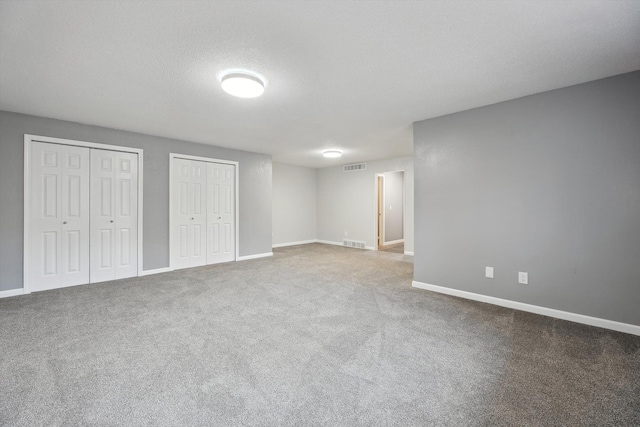 unfurnished bedroom featuring visible vents, multiple closets, and baseboards