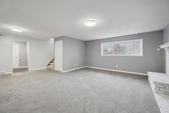 unfurnished living room with visible vents, a textured ceiling, carpet, a fireplace, and stairs