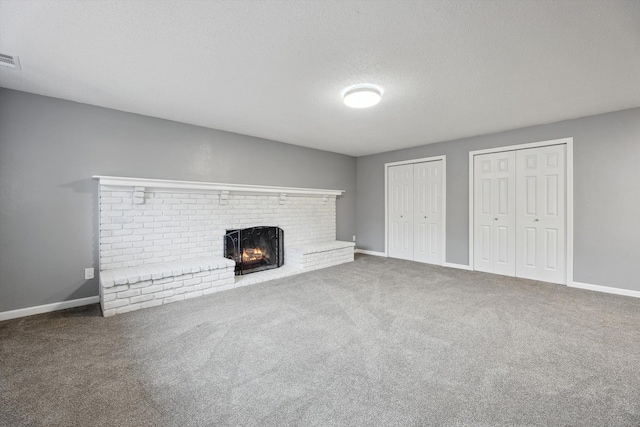 unfurnished living room with baseboards, carpet, a fireplace, and a textured ceiling