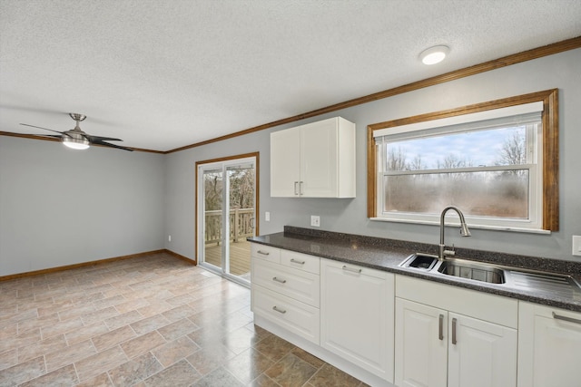 kitchen featuring dark countertops, plenty of natural light, white cabinets, and a sink