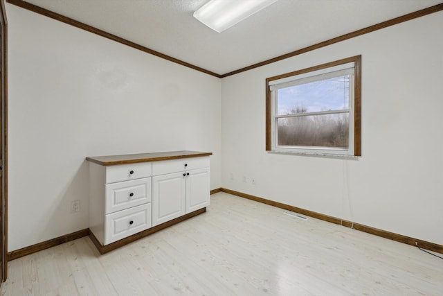 empty room featuring light wood-type flooring, baseboards, visible vents, and crown molding