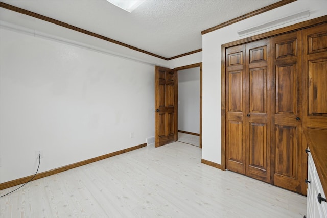 unfurnished bedroom featuring a textured ceiling, a closet, light wood-style floors, crown molding, and baseboards