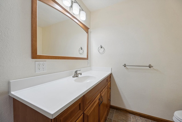 bathroom with toilet, vanity, and baseboards