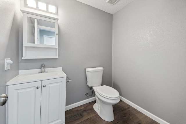 half bathroom featuring vanity, toilet, wood finished floors, and baseboards