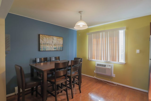 dining space featuring wood finished floors, baseboards, and a wall mounted air conditioner