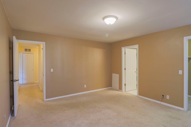 spare room with light colored carpet, visible vents, and baseboards