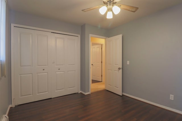 unfurnished bedroom featuring dark wood-style floors, a closet, and baseboards