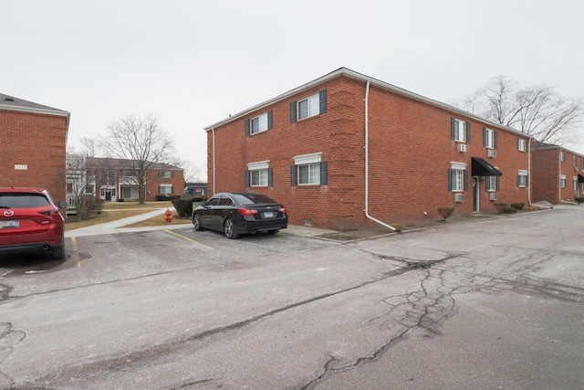 exterior space with uncovered parking and brick siding