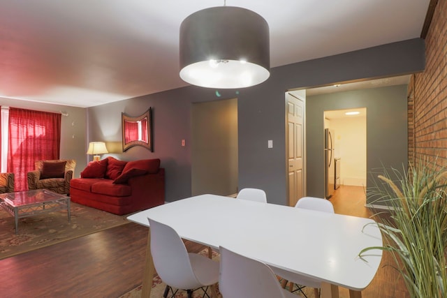 dining space featuring brick wall and wood finished floors