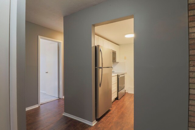 corridor featuring dark wood-type flooring and baseboards