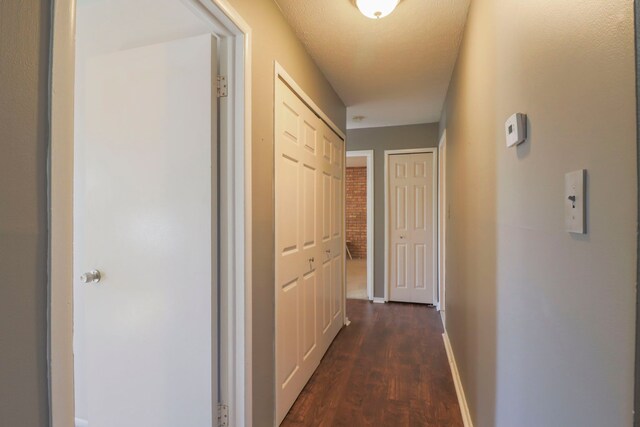 corridor featuring baseboards and dark wood-style flooring