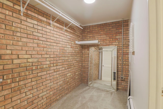 carpeted empty room with baseboard heating and brick wall