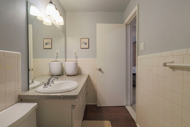 bathroom with a wainscoted wall, tile walls, wood finished floors, and vanity