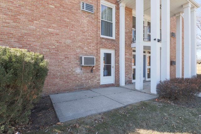 property entrance with brick siding and a wall mounted air conditioner