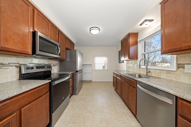 kitchen featuring baseboards, appliances with stainless steel finishes, decorative backsplash, and a sink