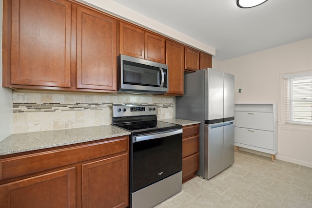 kitchen with stainless steel appliances, brown cabinets, backsplash, and light stone countertops