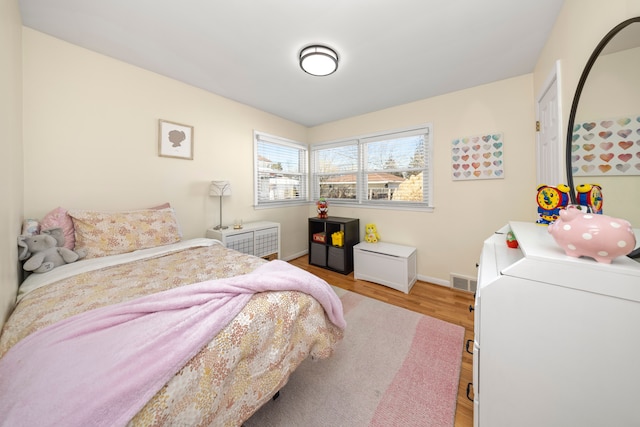 bedroom with visible vents, baseboards, and wood finished floors