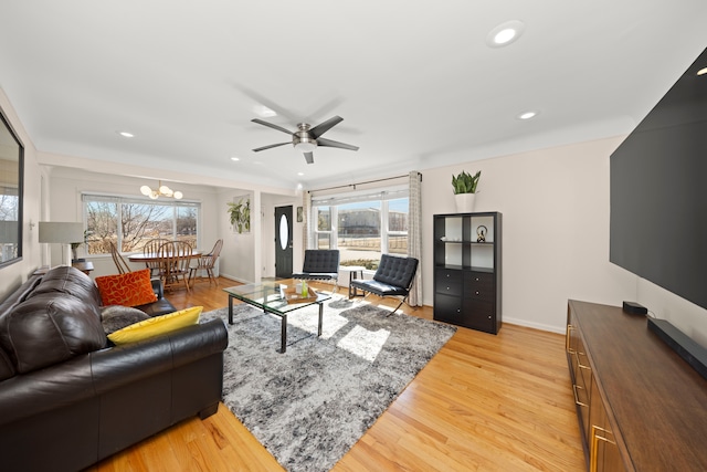 living room with light wood-style floors, ceiling fan with notable chandelier, baseboards, and recessed lighting