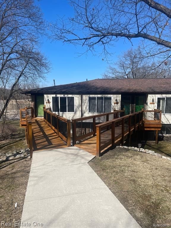 view of front of property featuring a shingled roof and a wooden deck