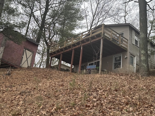 back of property featuring a storage shed, a wooden deck, and an outbuilding