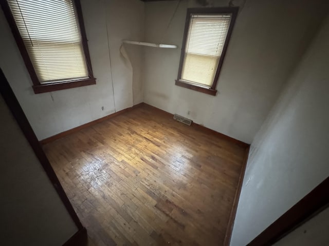 unfurnished room featuring hardwood / wood-style flooring, plenty of natural light, and visible vents