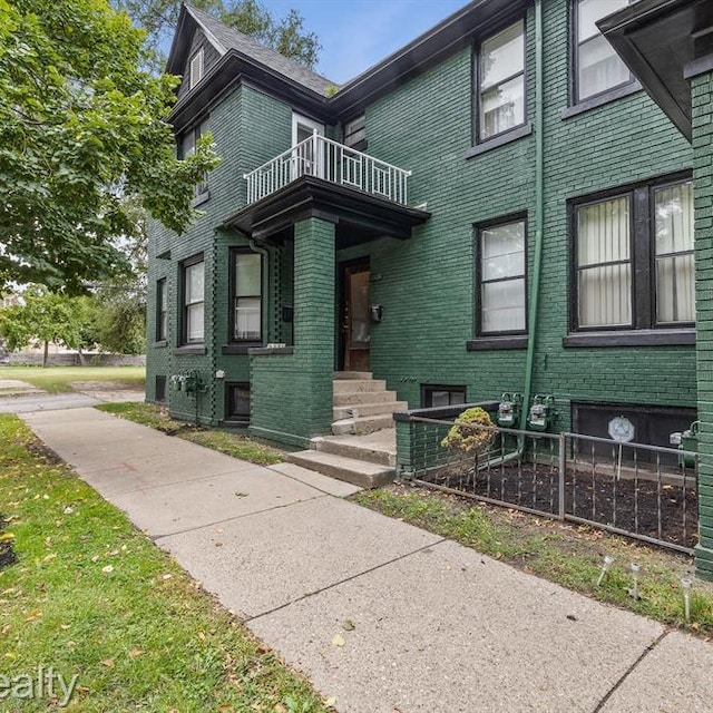 view of front of property with brick siding and a balcony