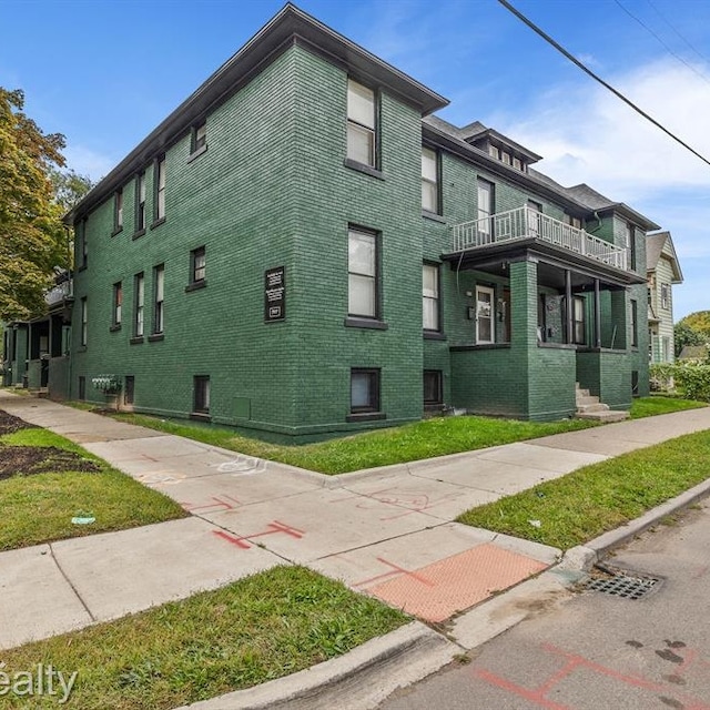 view of side of home featuring a balcony and brick siding